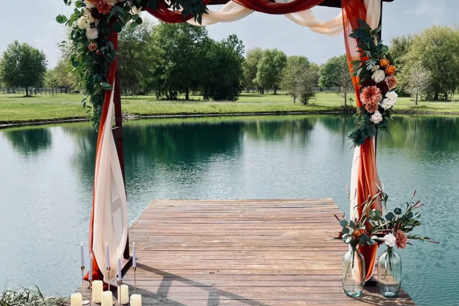 Floral ceremony arch draped in ribbon on a lakeside dock