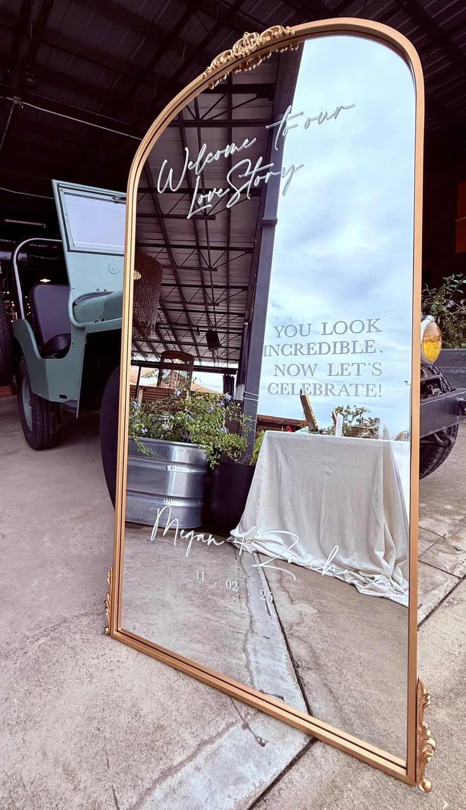 A gold arched mirror welcome sign standing on a concrete patio