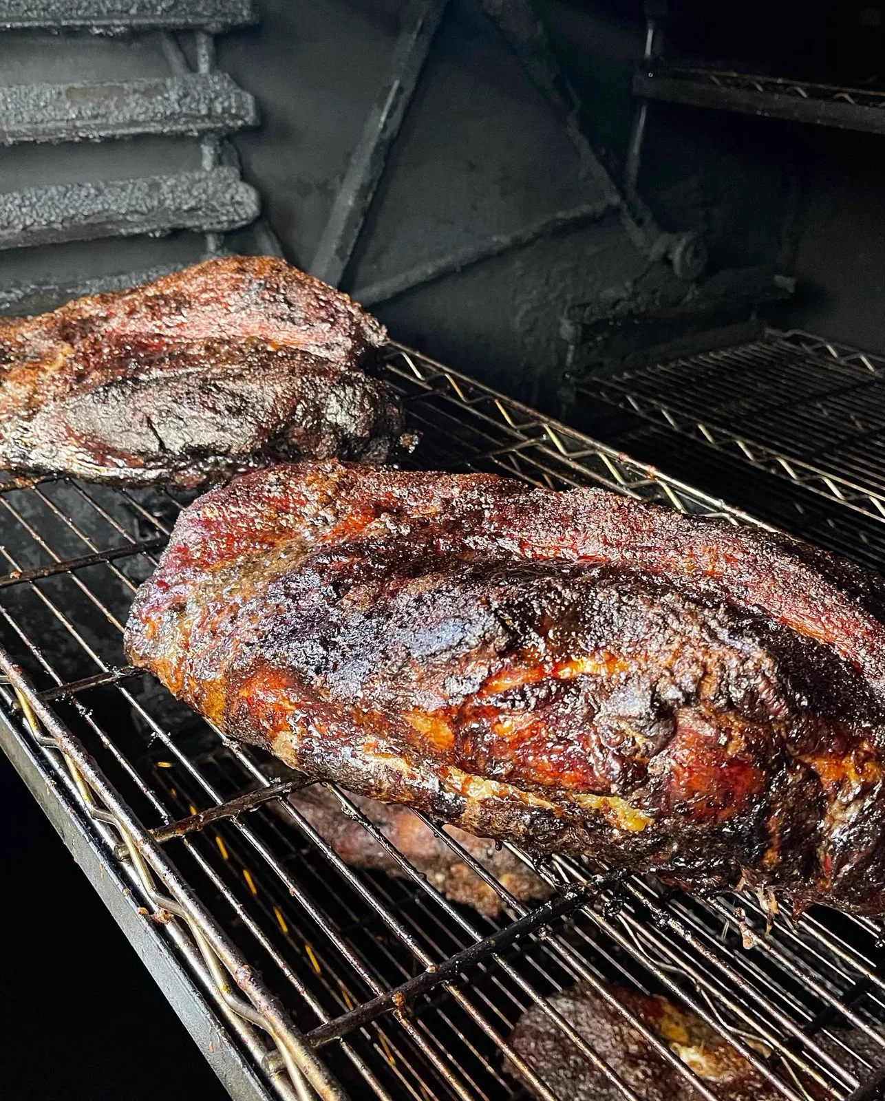 Two whole smoked roasts resting on the smoker grates